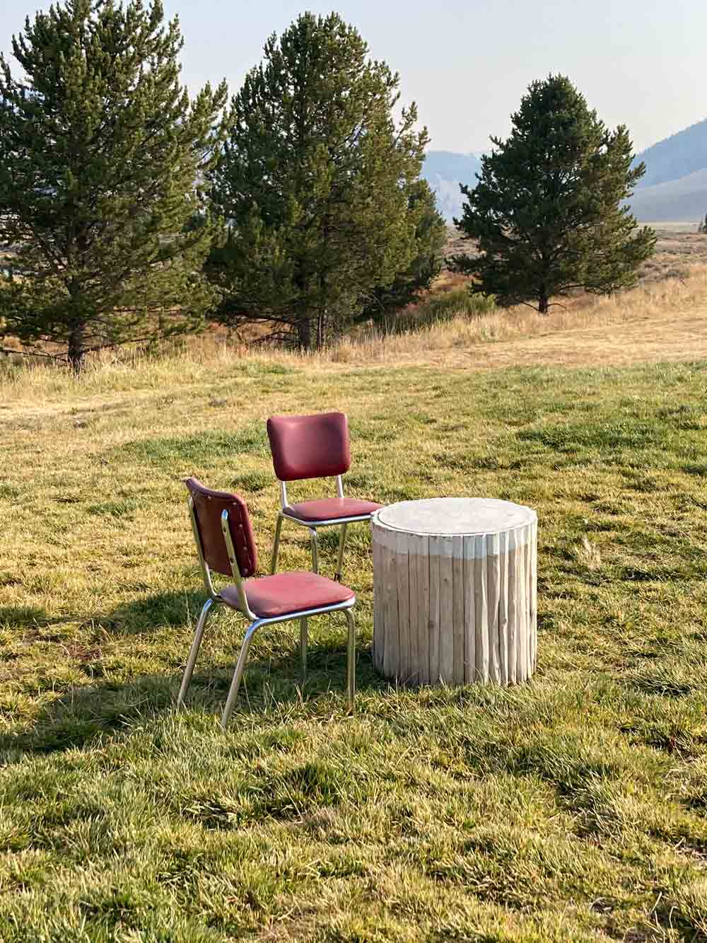 two chairs at rustic table with mountains in background